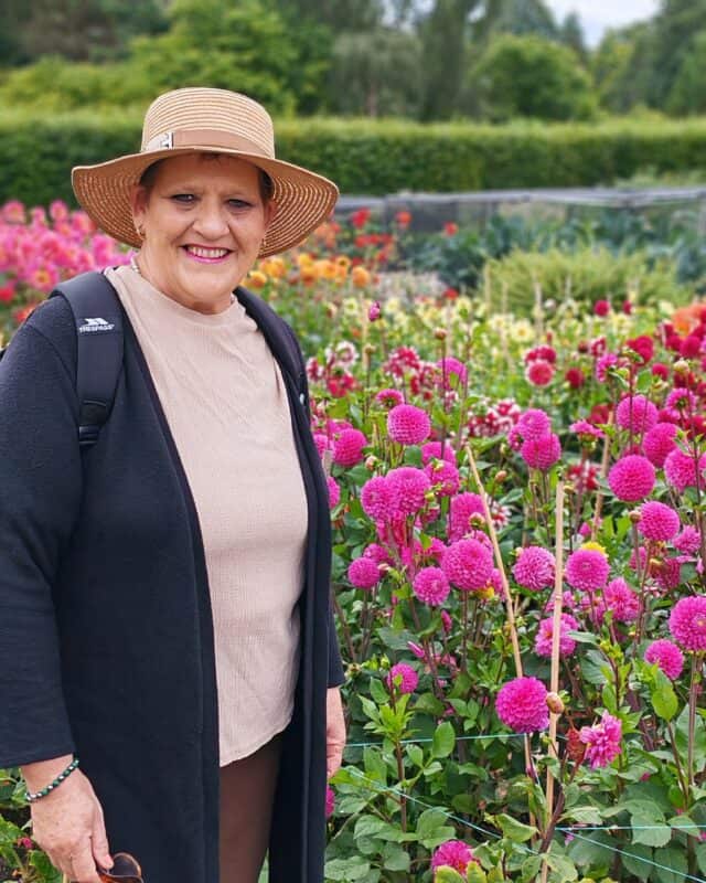 A woman with a hat in a flower garden.