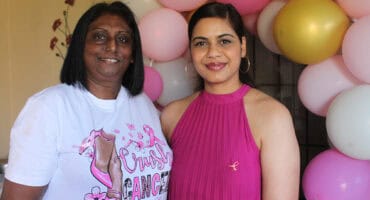 Two women standing in front of balloons.