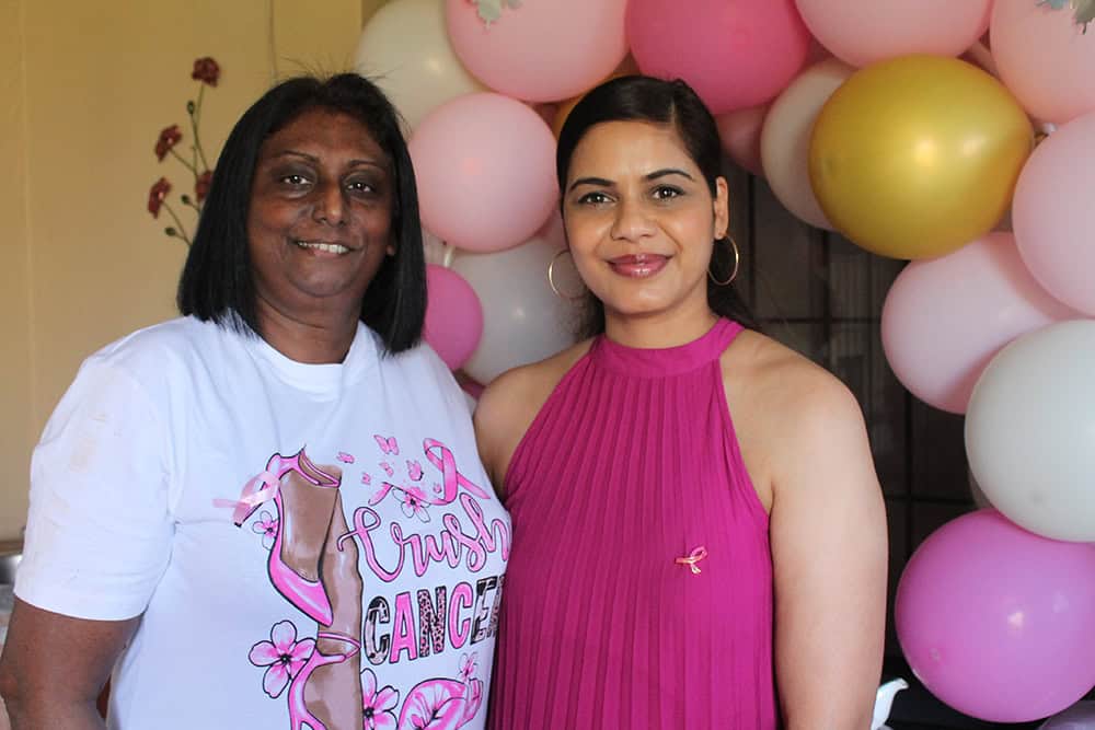 Two women standing in front of balloons.