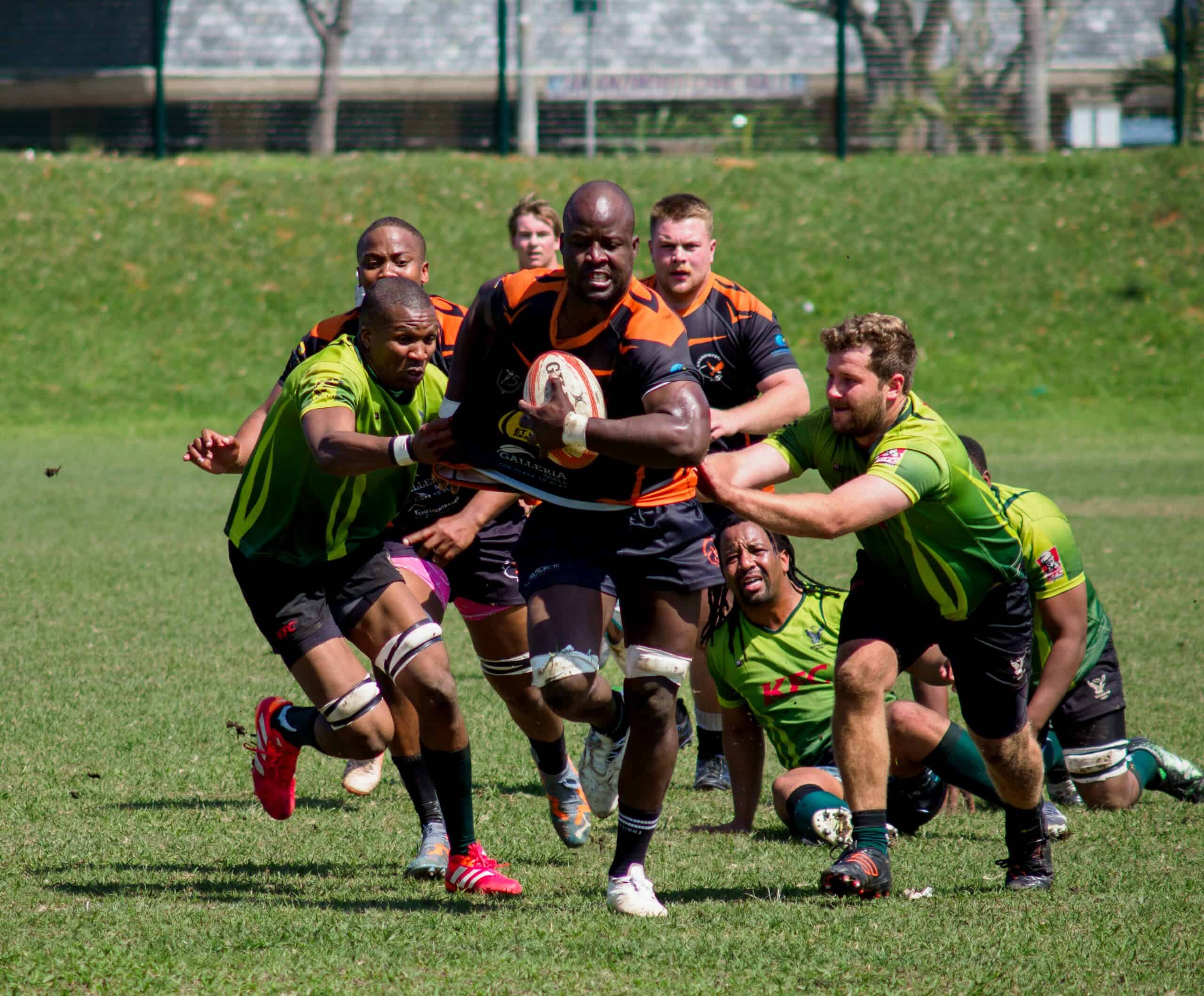 A rugby player fending off multiple rugby players of the other team.