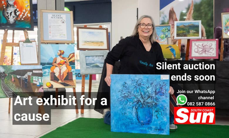 A woman holding up a painting. In the background, there are multiple paintings.