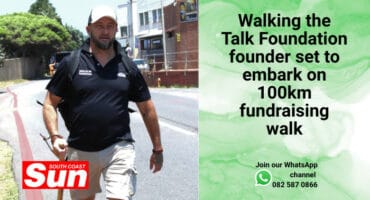 A man walking along the road with a walking stick.