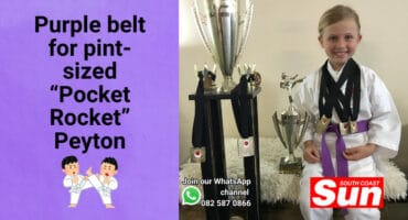 A young girl in karate Ghi, next to her trophies.