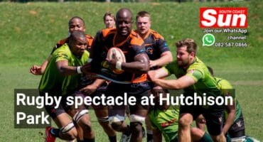 A rugby player fending off multiple rugby players of the other team.