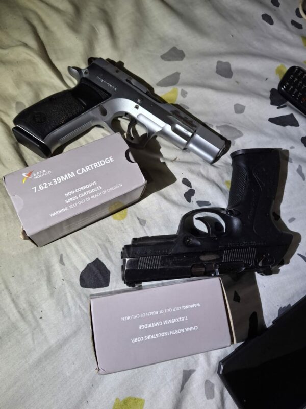 Two pistols and two boxes containing bullets on a bed