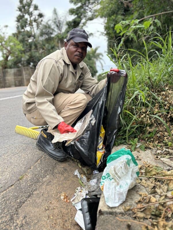 A man picking up dirt and putting it in a trash bag.