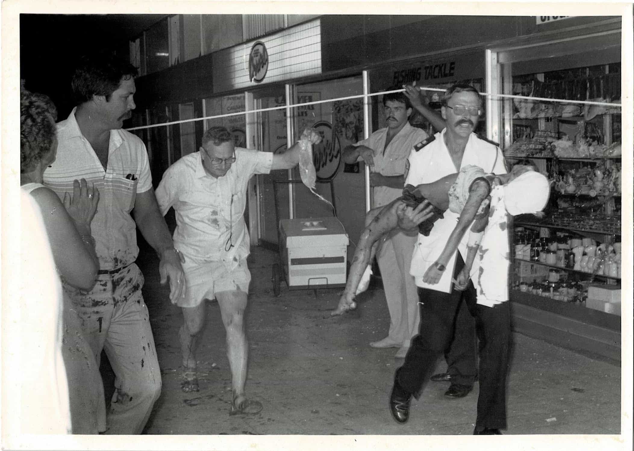 A paramedic carrying an injured child away from a mall. 