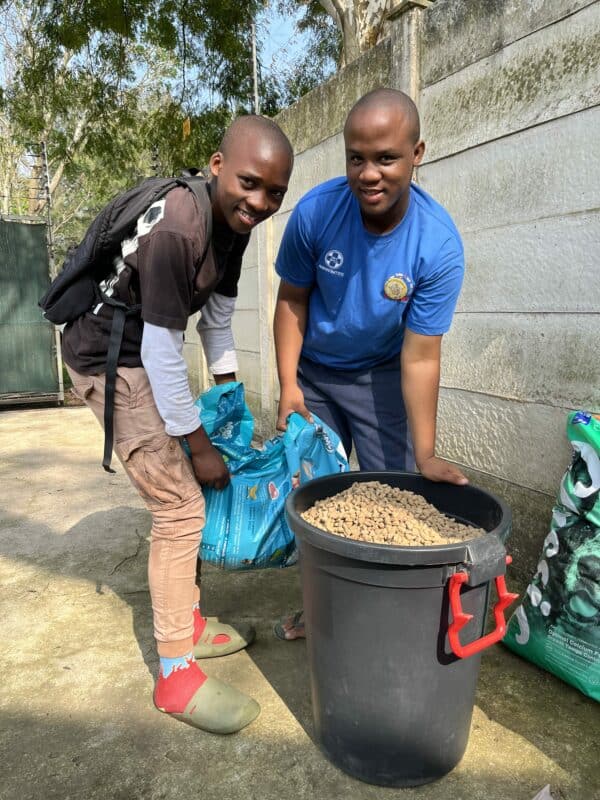 A child and a man with a bucket of dog food.