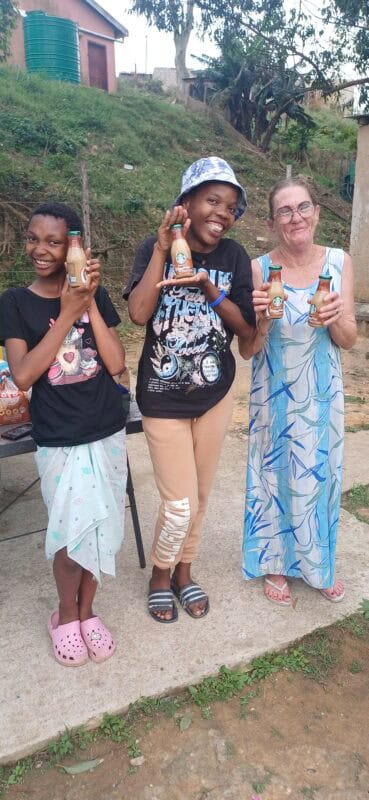 Three women smiling holding bottles.