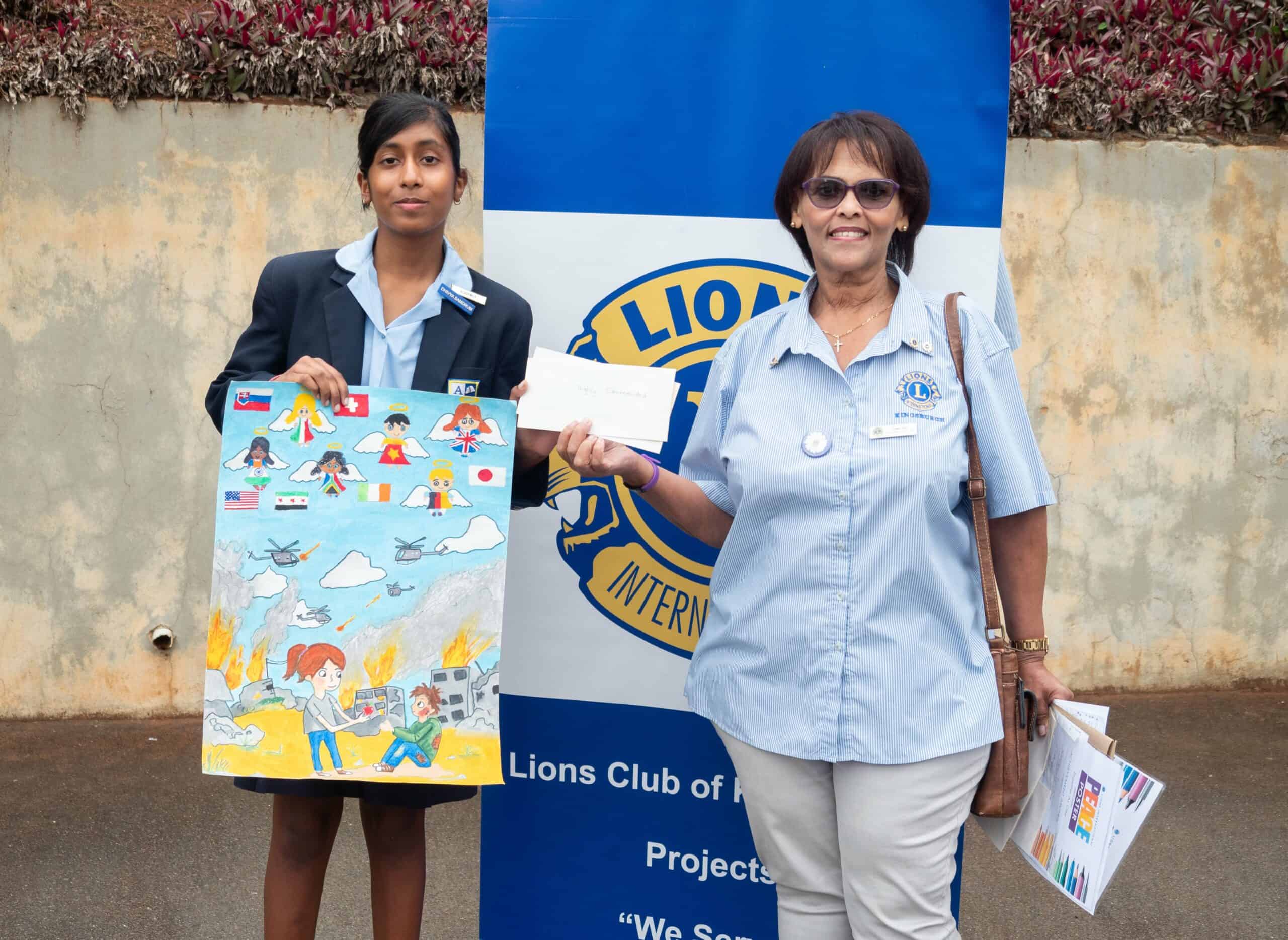 A school child holding up her artwork, receiving her award from another woman.