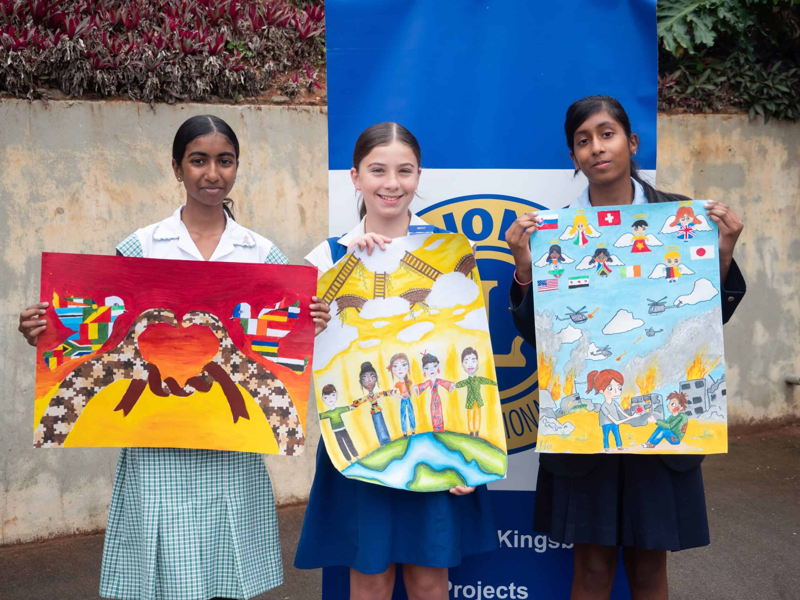 School children holding up peace posters they designed.