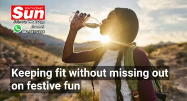 A woman drinking water while on a hike.
