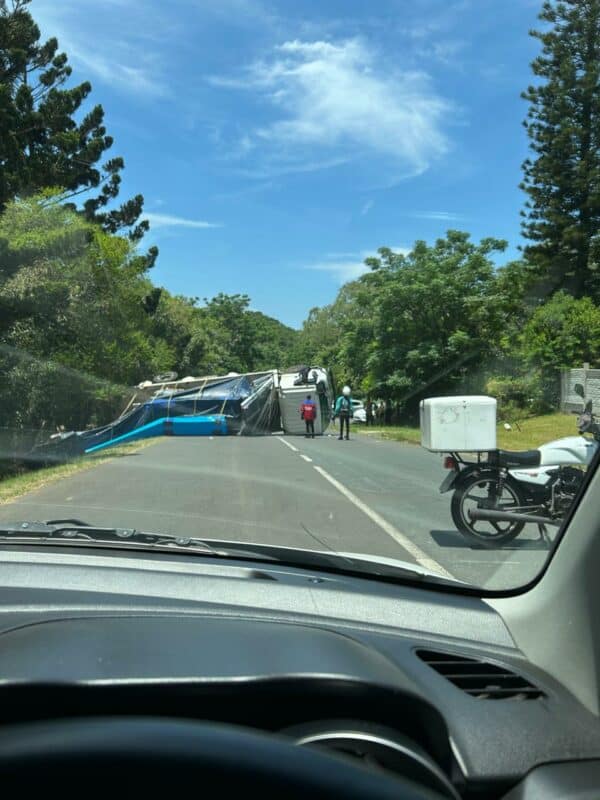 A photograph of an overturned truck taken from inside a vehicle.