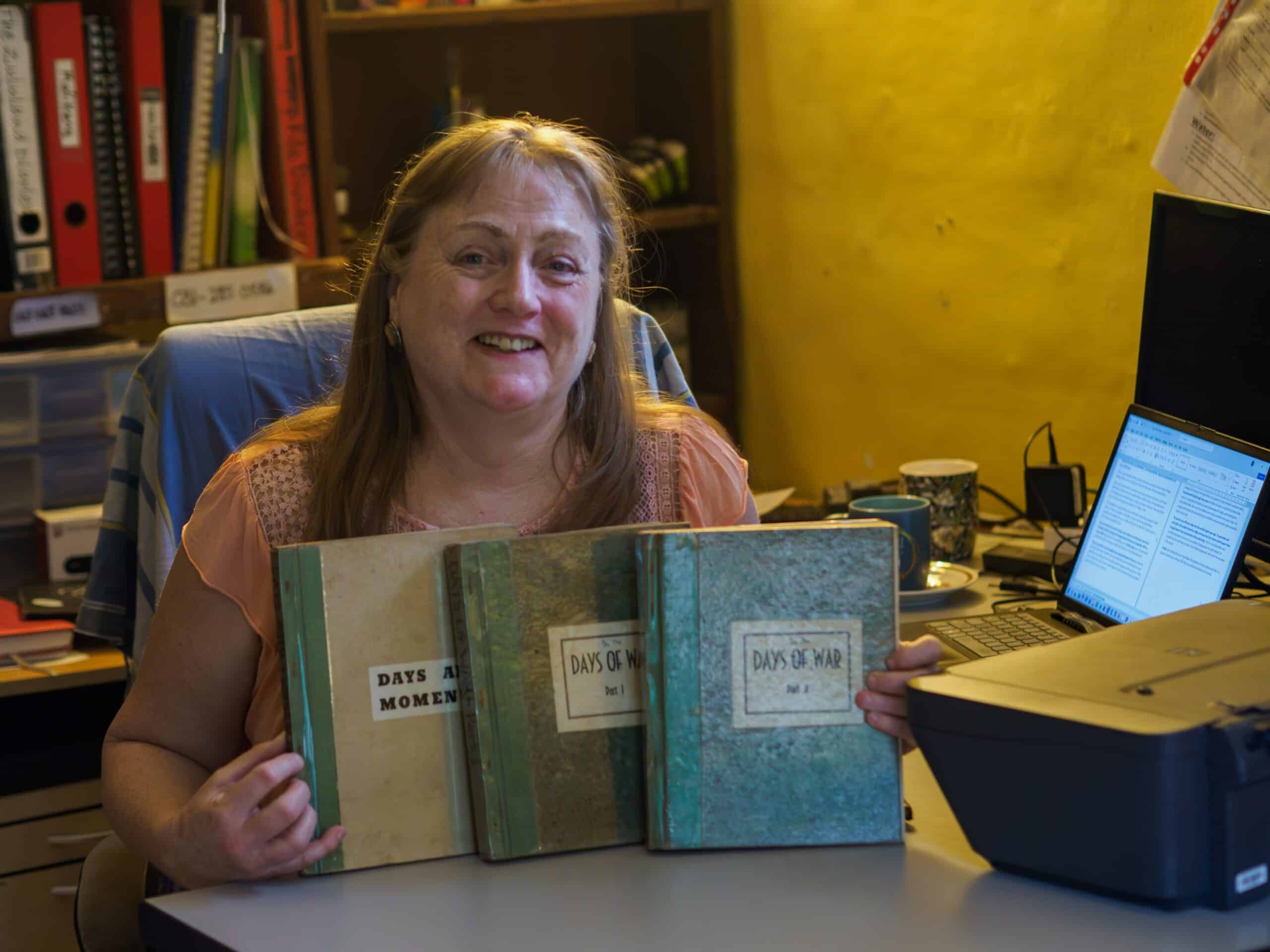 A woman holding three books.