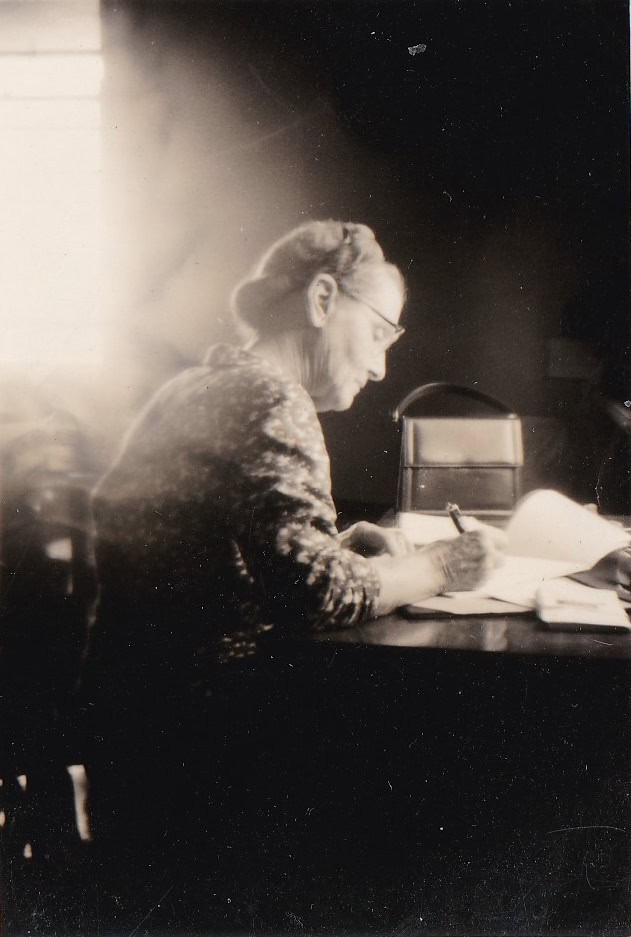A photograph of a woman writing in a diary.