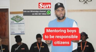 An adult is standing and addressing a group of seated boys.