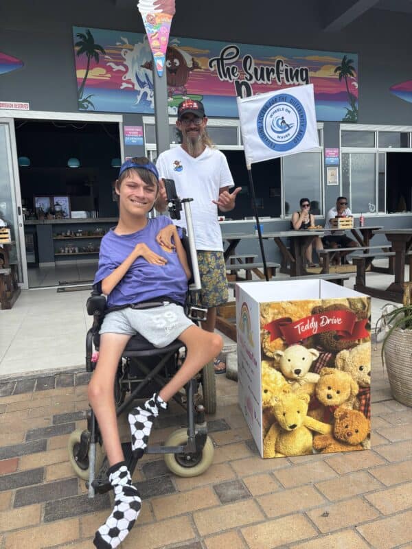 A paraplegic man and able-bodied man next to a donation box