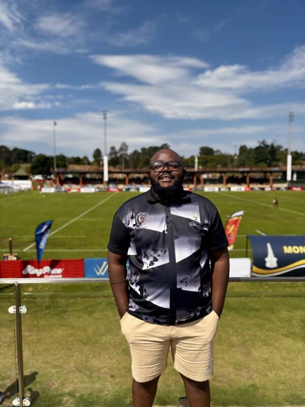 A rugby coach in front of a rugby field
