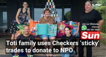 A group photograph. In the background is donated food items.