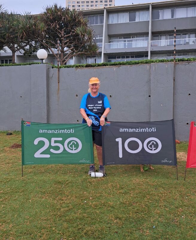 A female runner poses in front of two banners.