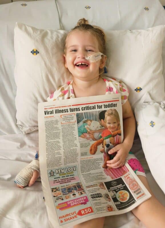 a little girl in hospital with a newspaper