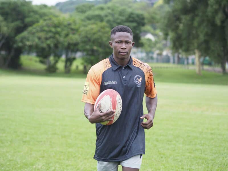 a rugby player holding a rugby ball jogging on the field