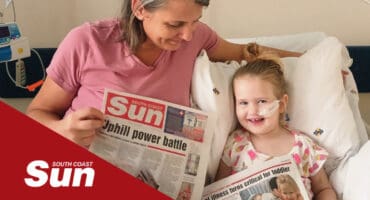 A mother and daughter in hospital holding a newspaper