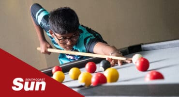 a young pool player lining up his shot
