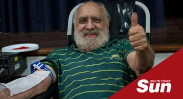 an elderly blood donor showing thumbs up