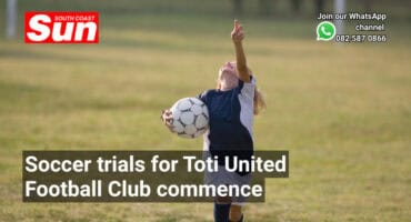 A girl on a soccer field, looking up, holding a ball.