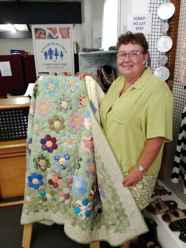 a woman shows a quilt