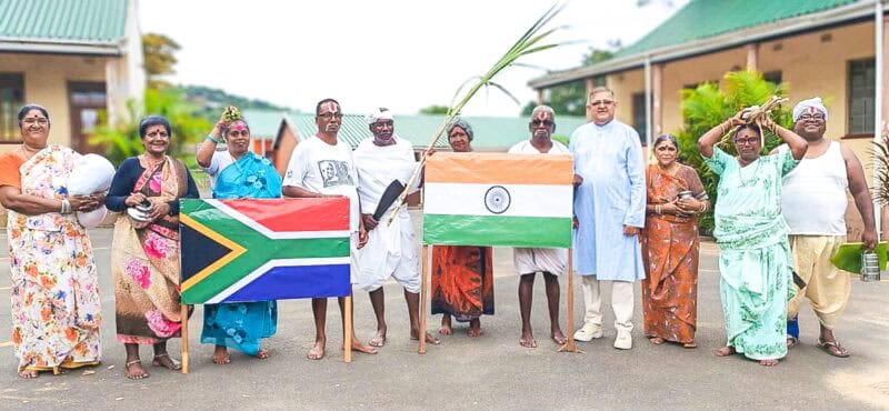 a group in cultural attire holding an indian and south african national flag