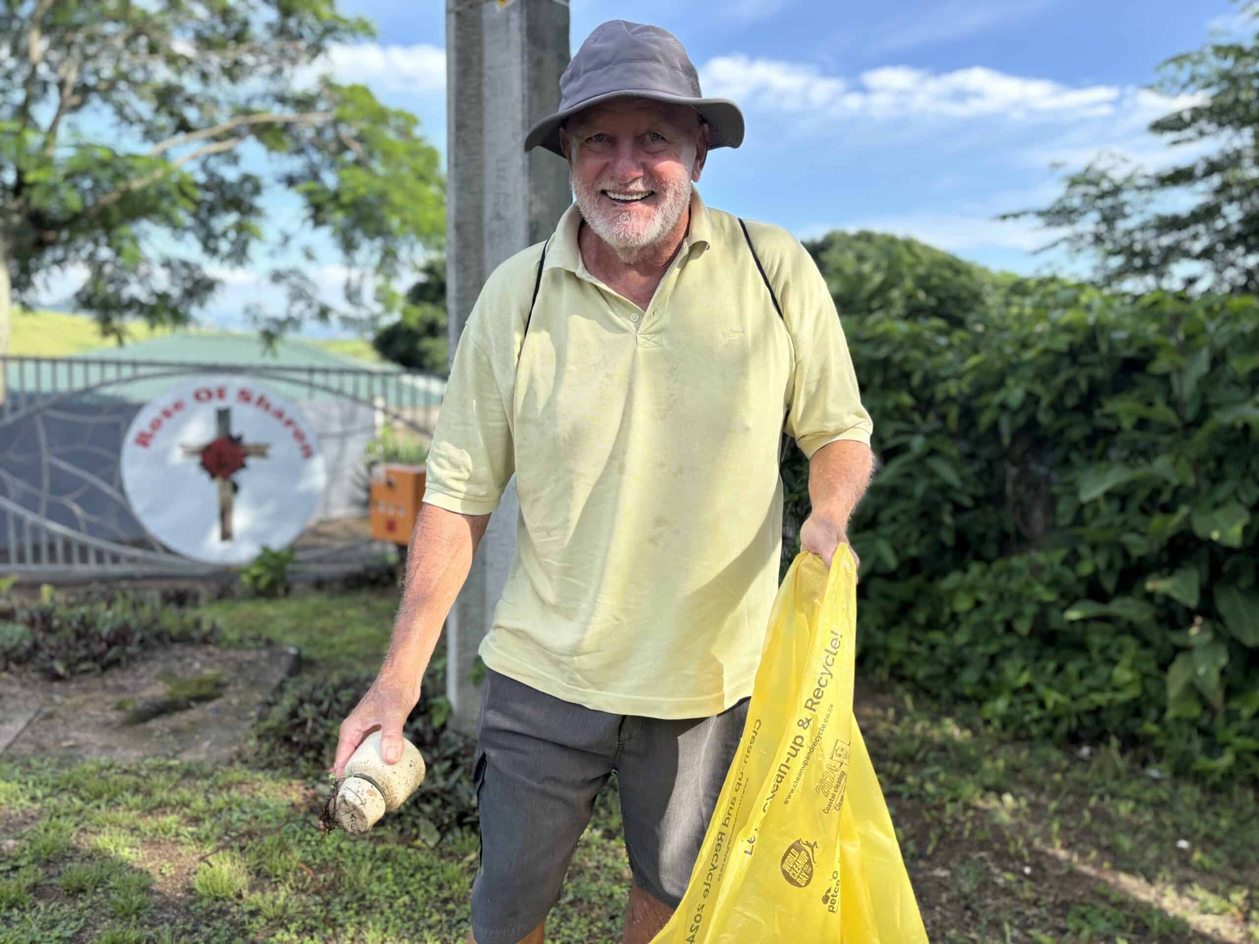 a person picking up litter, holding a refuse bag