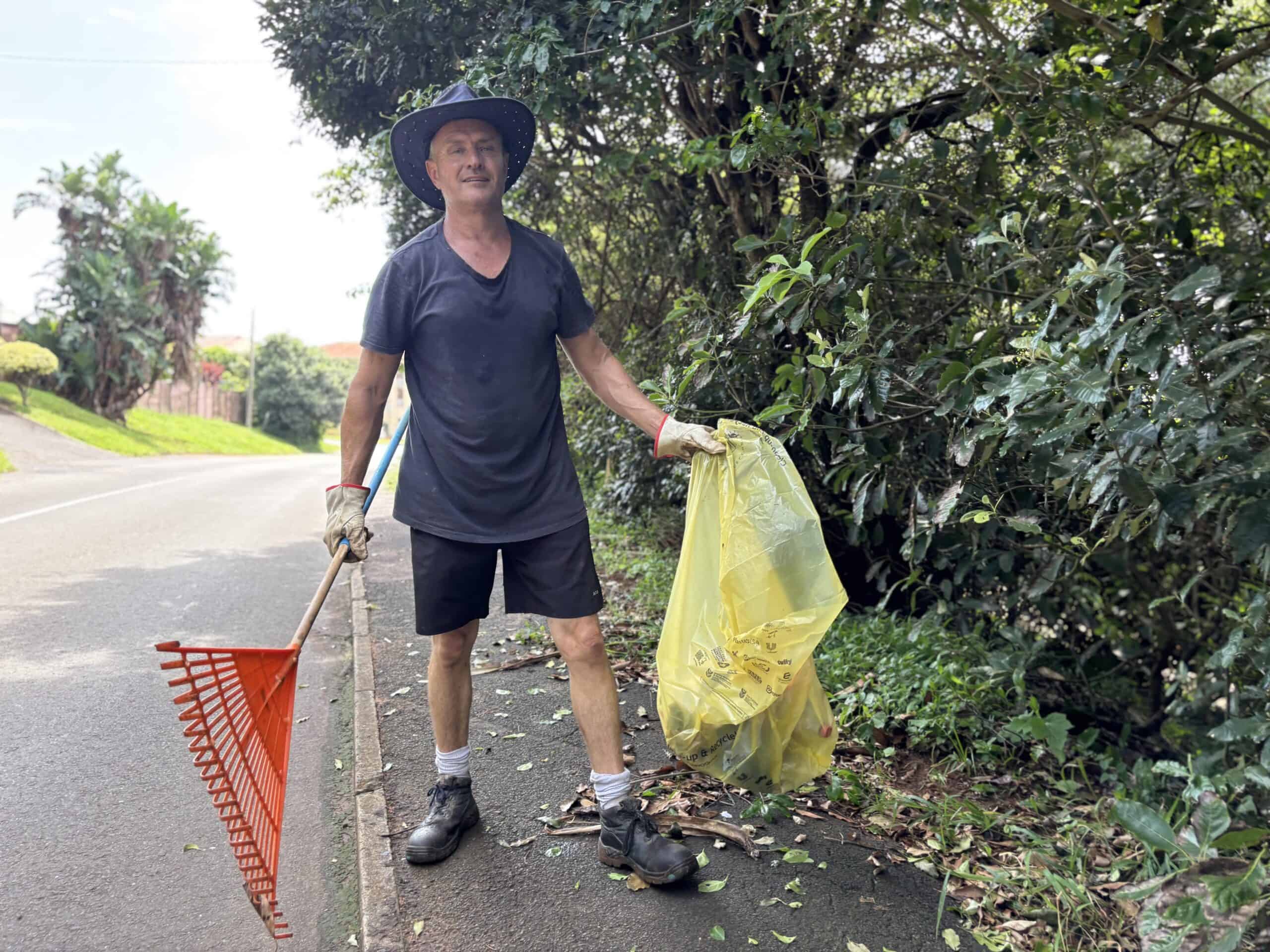a person picking up litter, holding a refuse bag