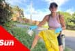 a woman picking up litter along a verge