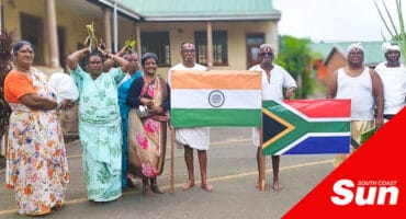 a group of people in traditional Indian attire holding indian and south african national flags