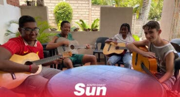 a group of neurodivergent teenagers playing guitar around a table