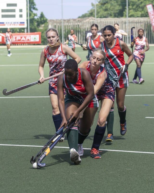 a hockey player with possession of the ball is being pressed by multiple defenders