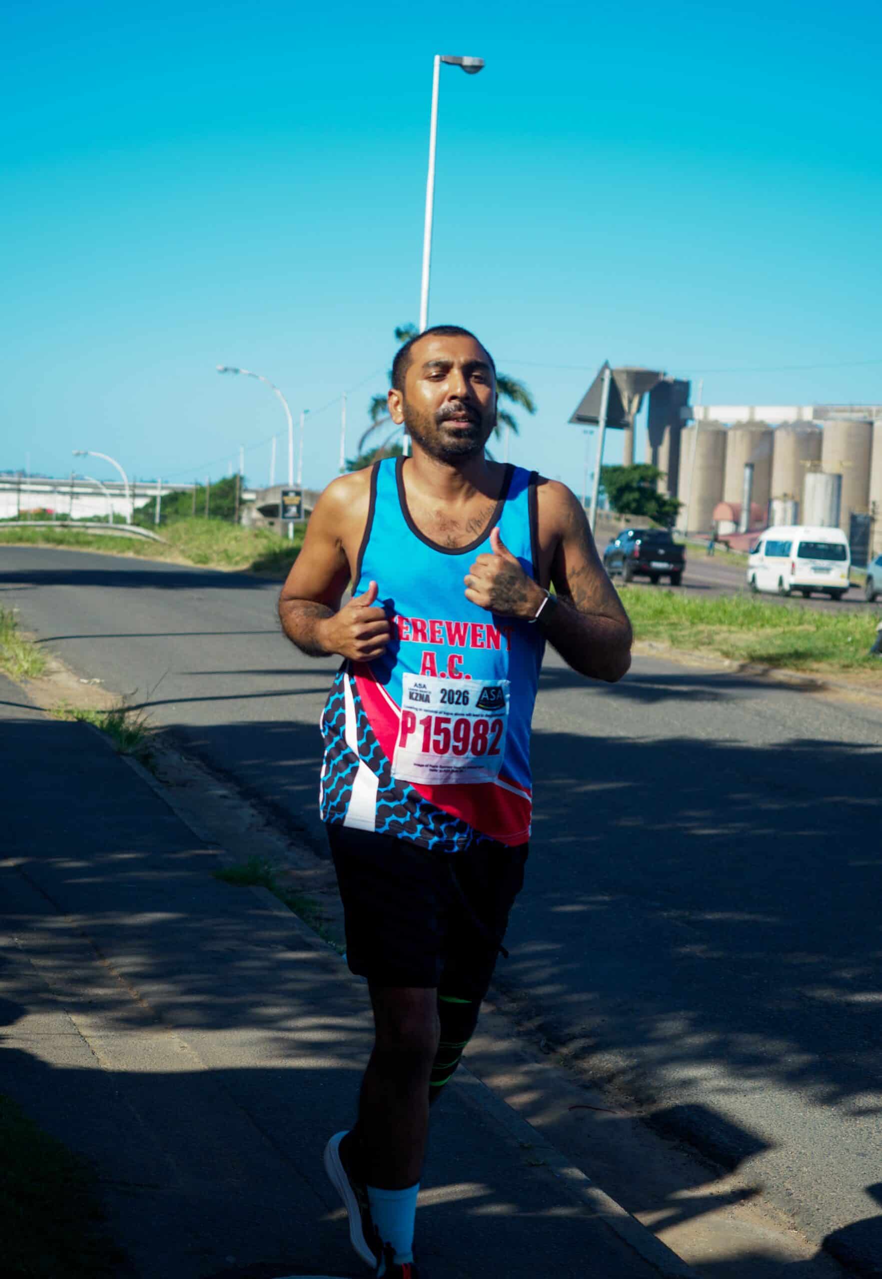 a runner in his athletic kit jogging along the pavement.