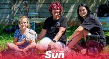 a child and two adults sitting on a carpet on grass