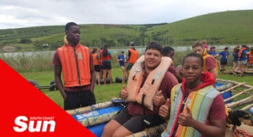 a scout troop with life jackets sitting in a makeshift raft