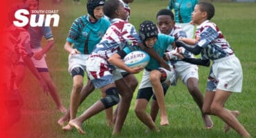 a rugby player with the ball pushing through multiple defenders