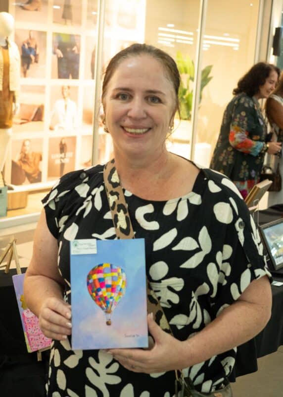 an artists showing their painting, smiling