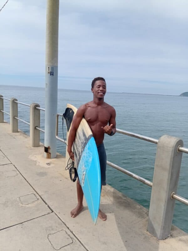 a surfer on a pier holding his surfboard