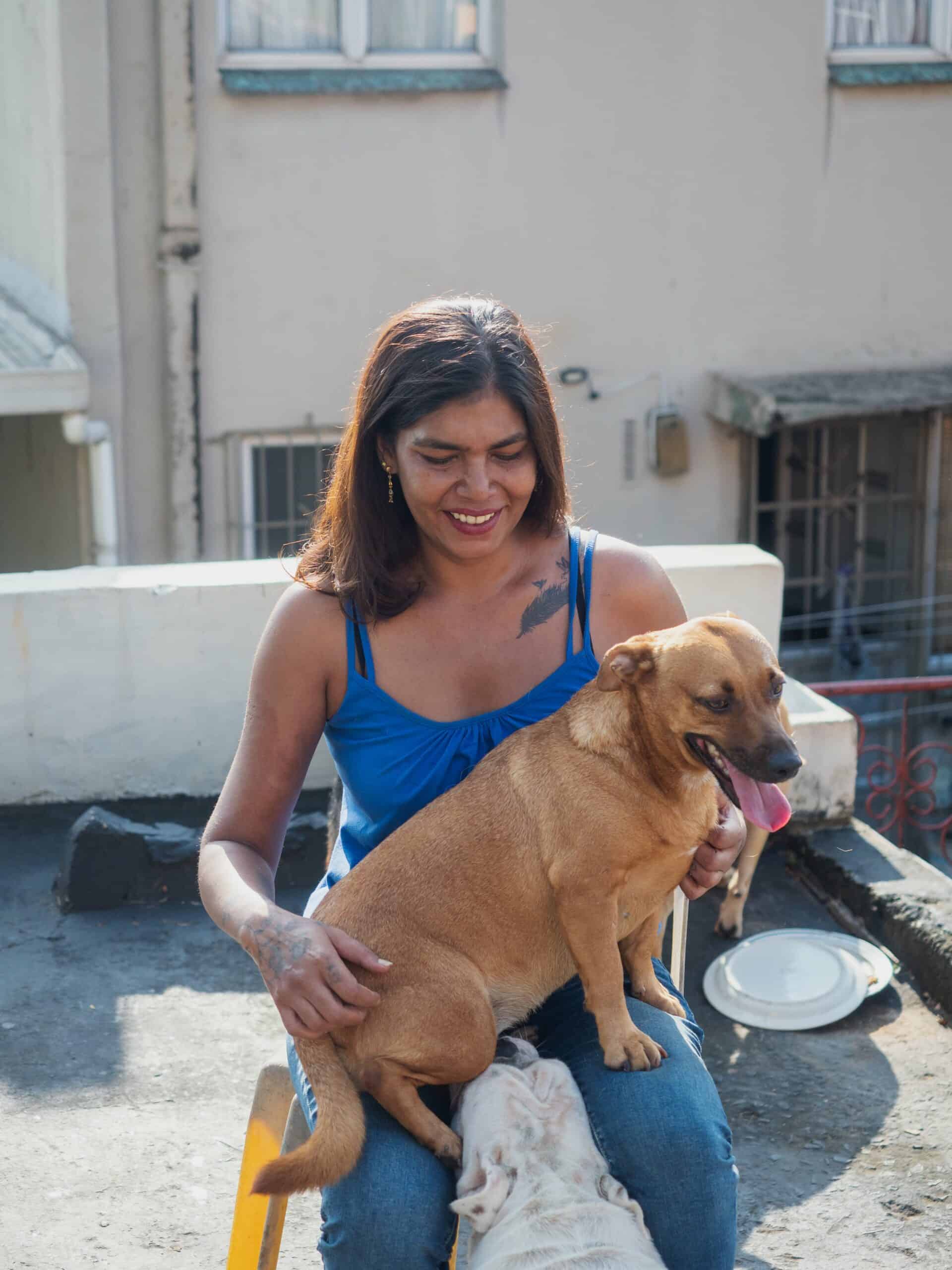 a woman sitting on a chair, holding a dog