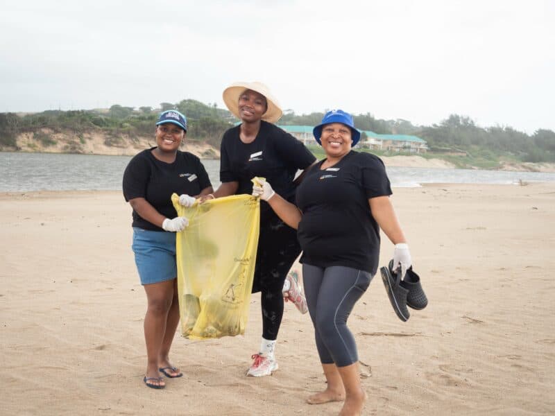 a trio of women holding a bag of litter on the beach