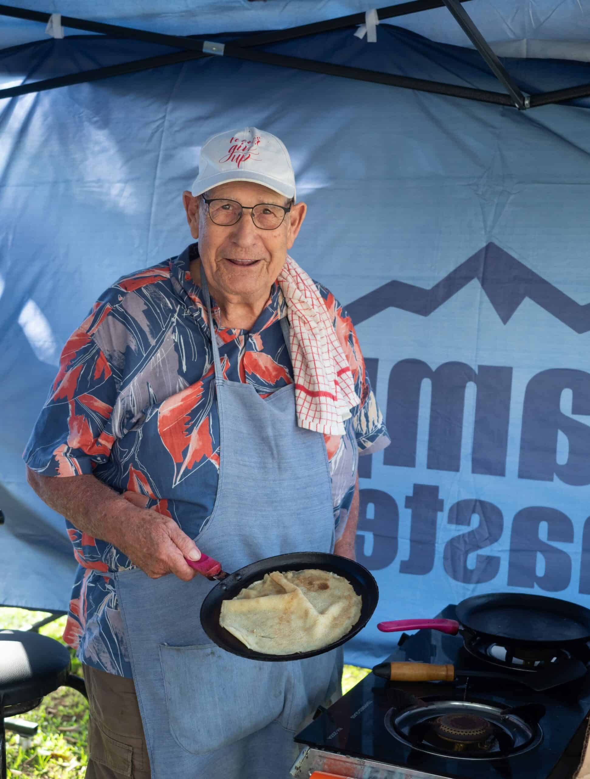 a man flipping pancakes at a market stall