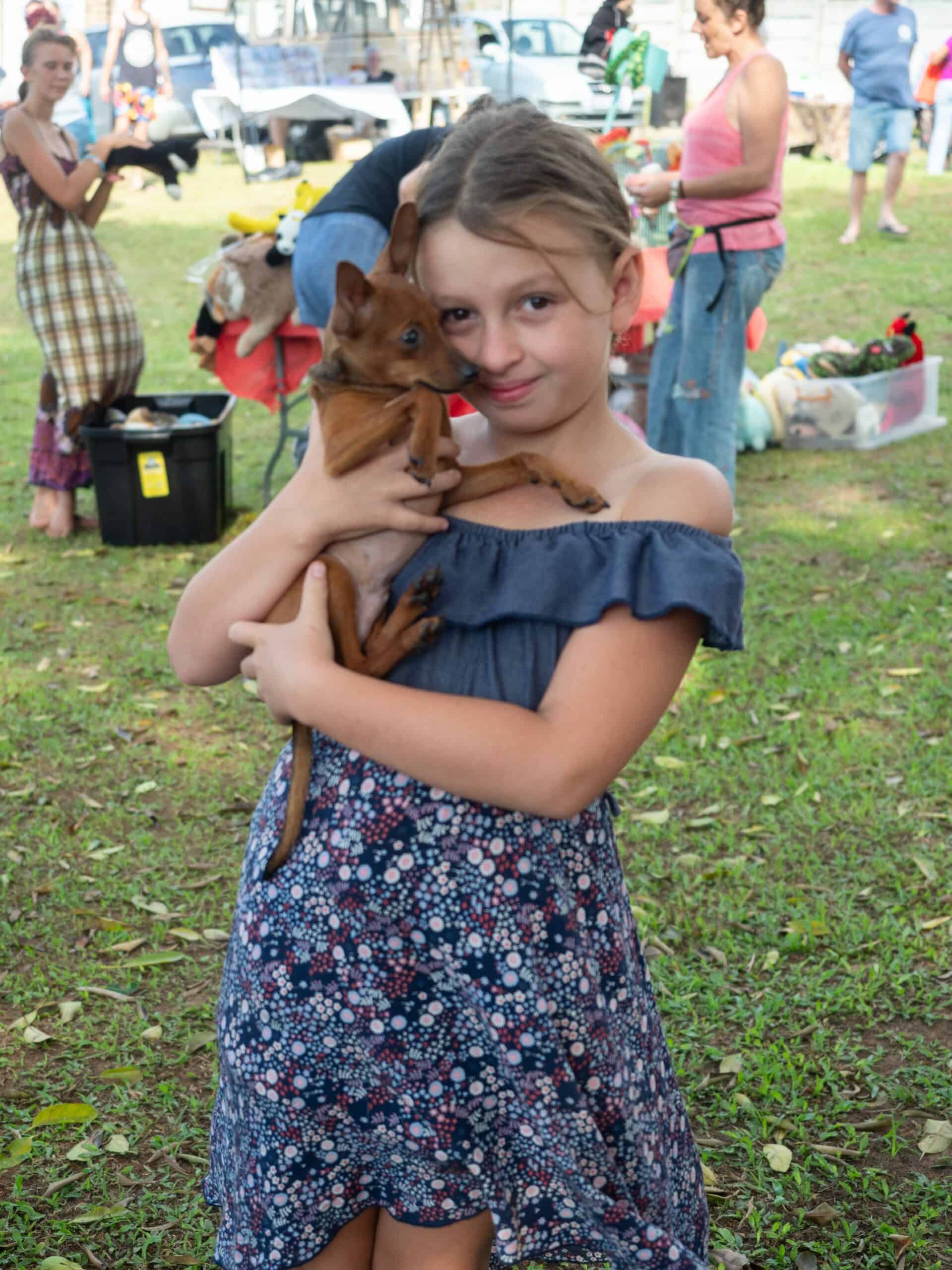 a little girl holding her puppy at a market