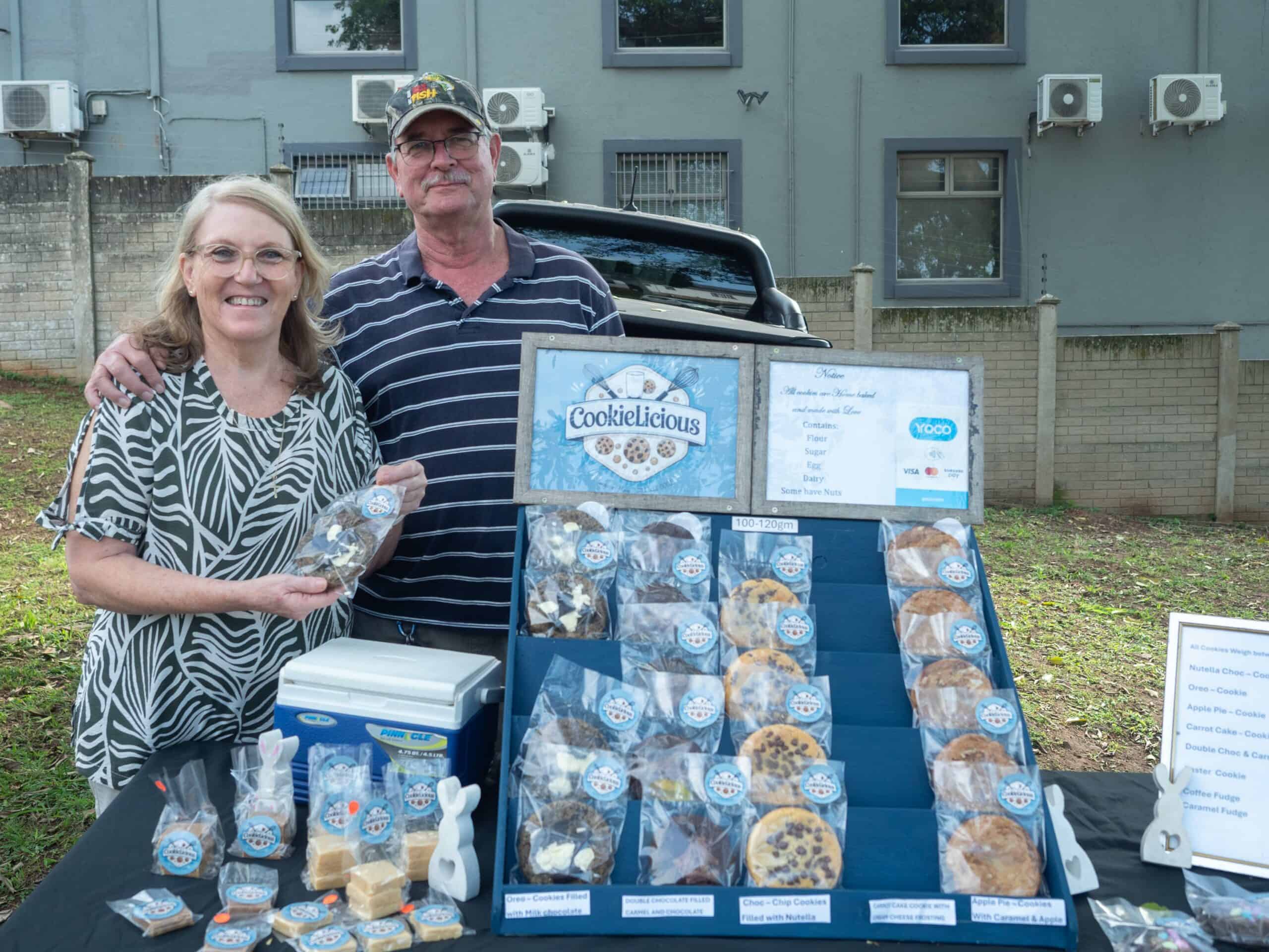 an elderly man and woman in front of their cookie market stall