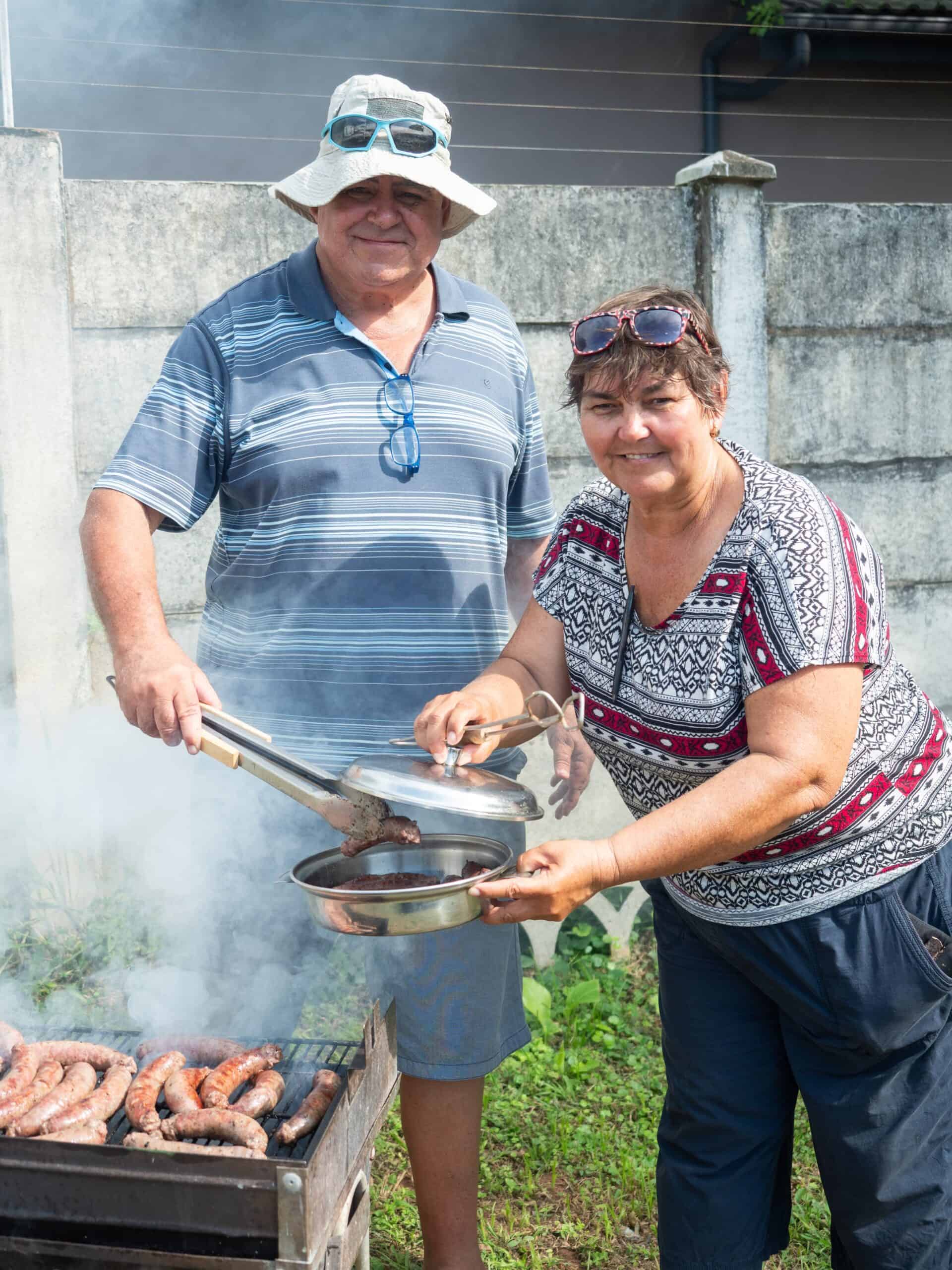 a man and woman grilling sausages outside